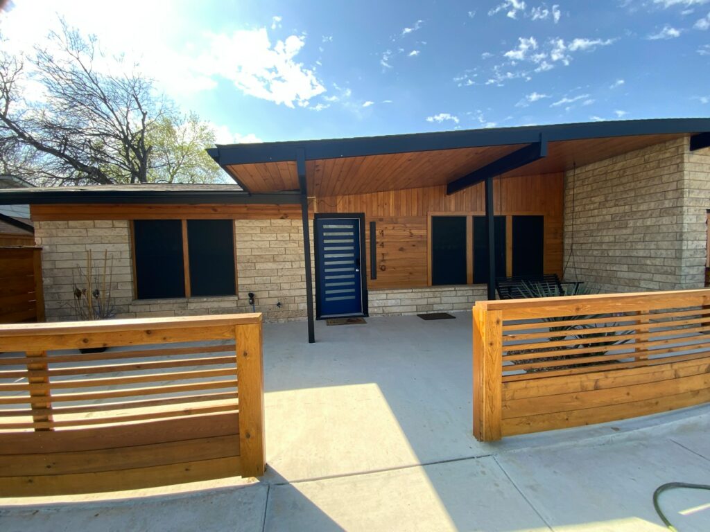 A house with a wooden fence and a blue door